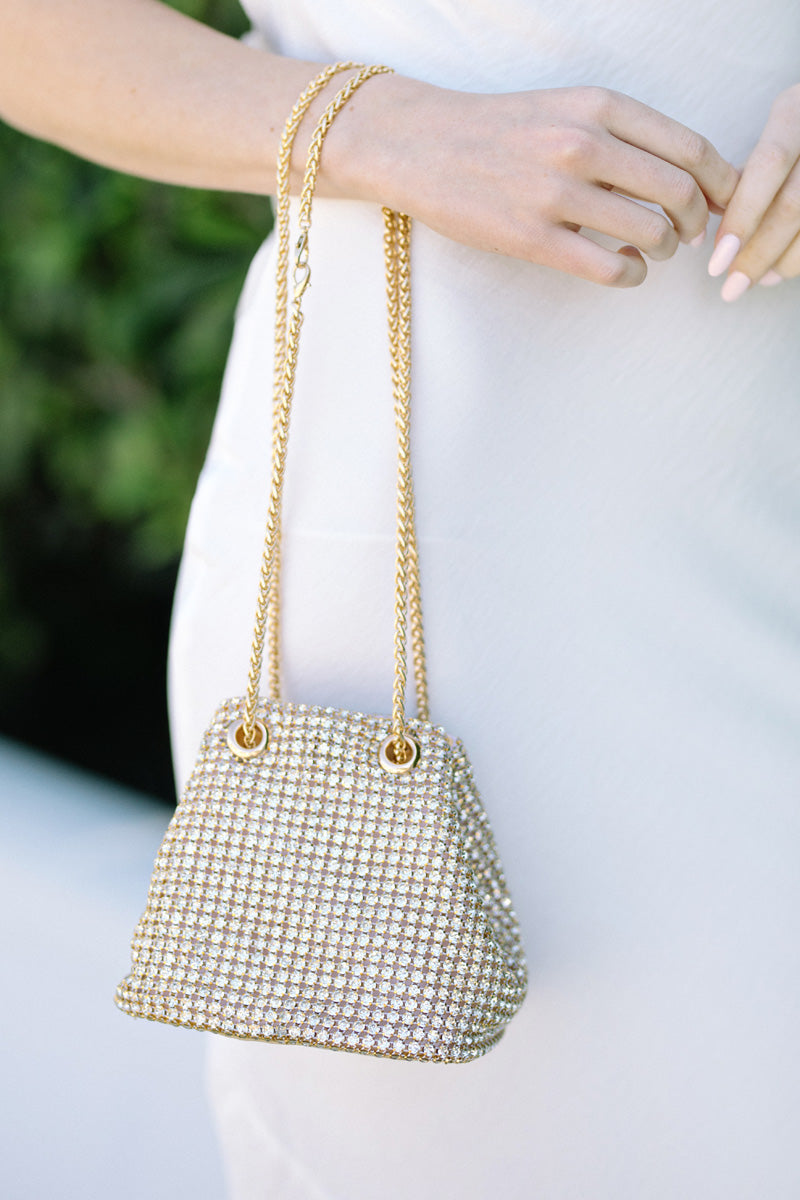 A gold-tone handbag with an intricate rhinestone grid pattern and dual chain straps, showcasing a stylish and eye-catching design.