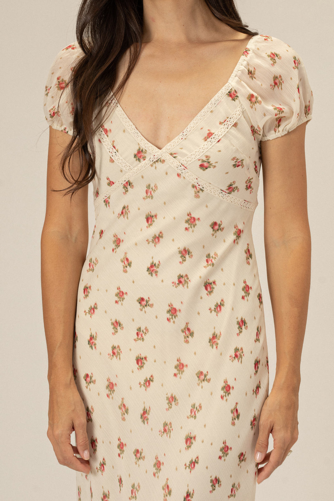 A cream-colored, floral-print dress with a V-neck, puffed sleeves, and lace accents, showcasing a flattering, fitted silhouette.