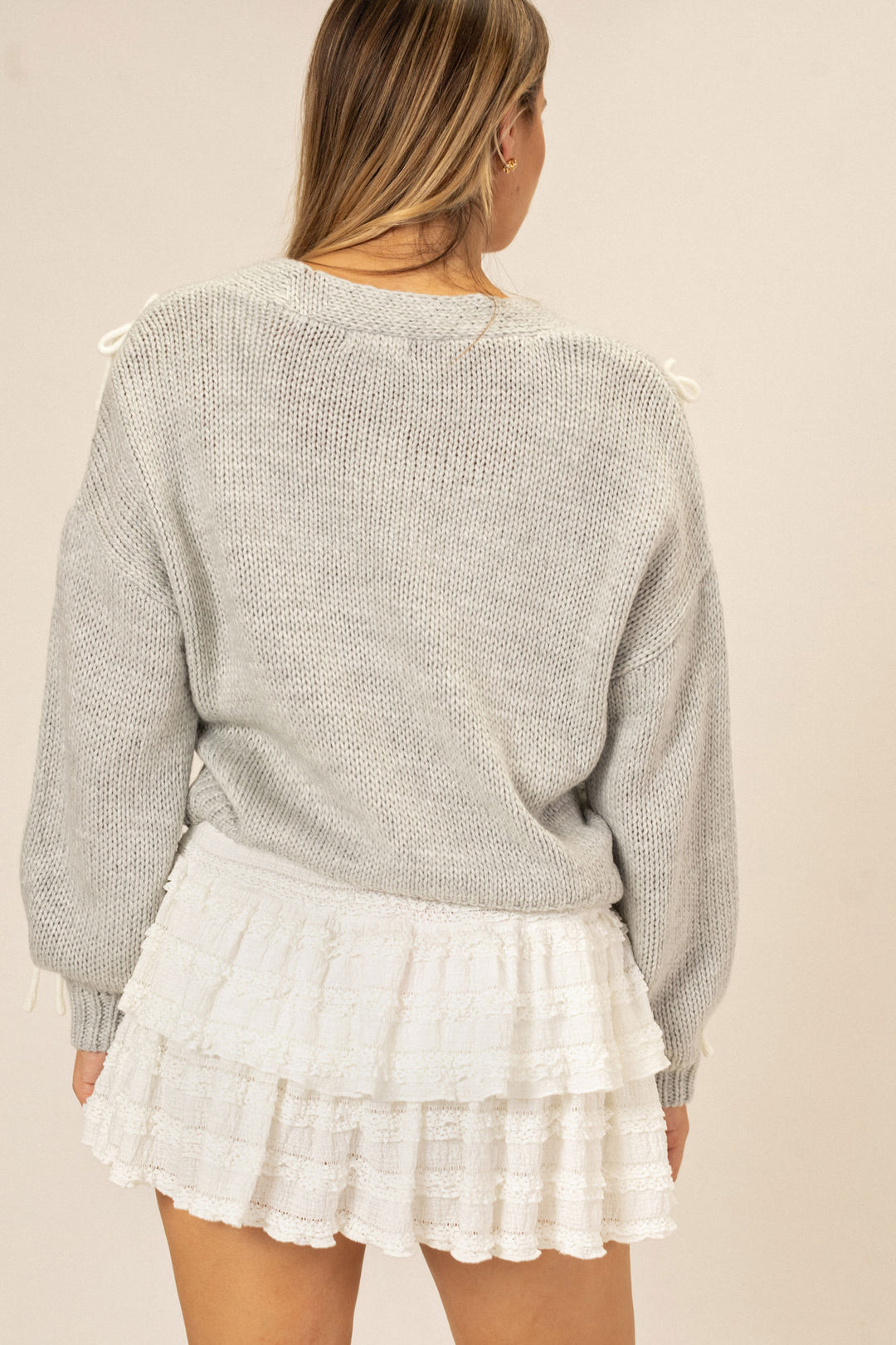 A cozy gray knit sweater paired with a tiered, lace-trimmed white mini skort, creating a stylish and feminine look.
