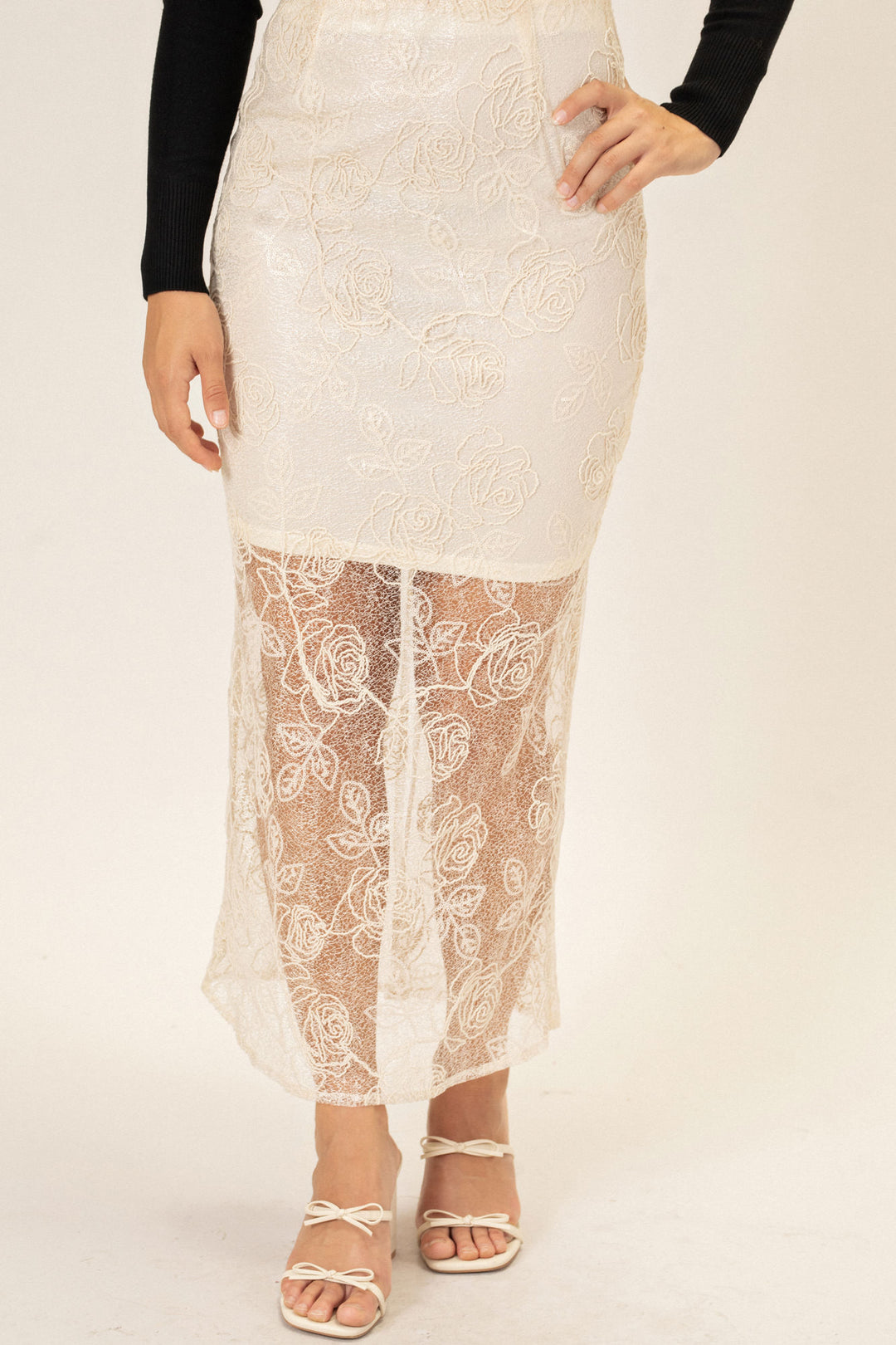 A long, flowy white lace skirt with intricate floral patterns across the fabric, designed for a graceful, feminine look.