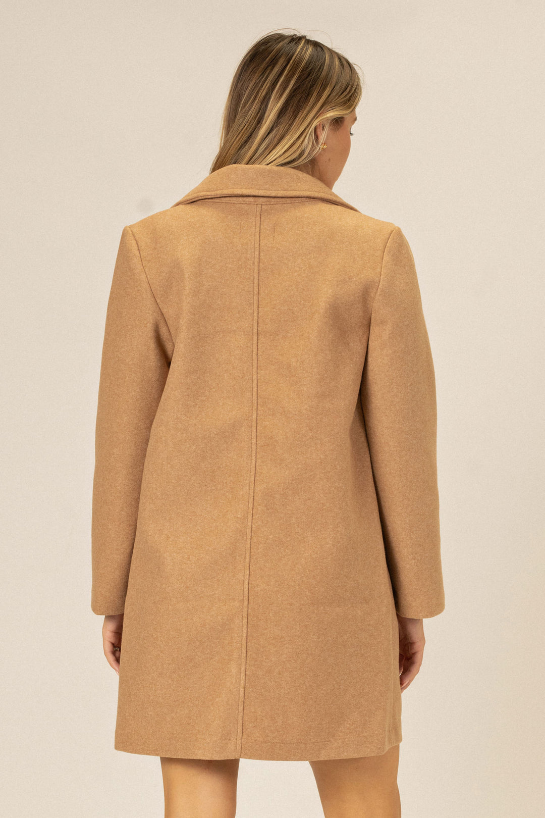 A camel-colored, notched lapel coat with an A-line silhouette and a hidden button closure, shown from the back.