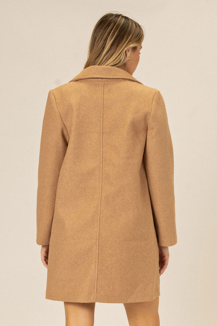 A camel-colored, notched lapel coat with an A-line silhouette and a hidden button closure, shown from the back.