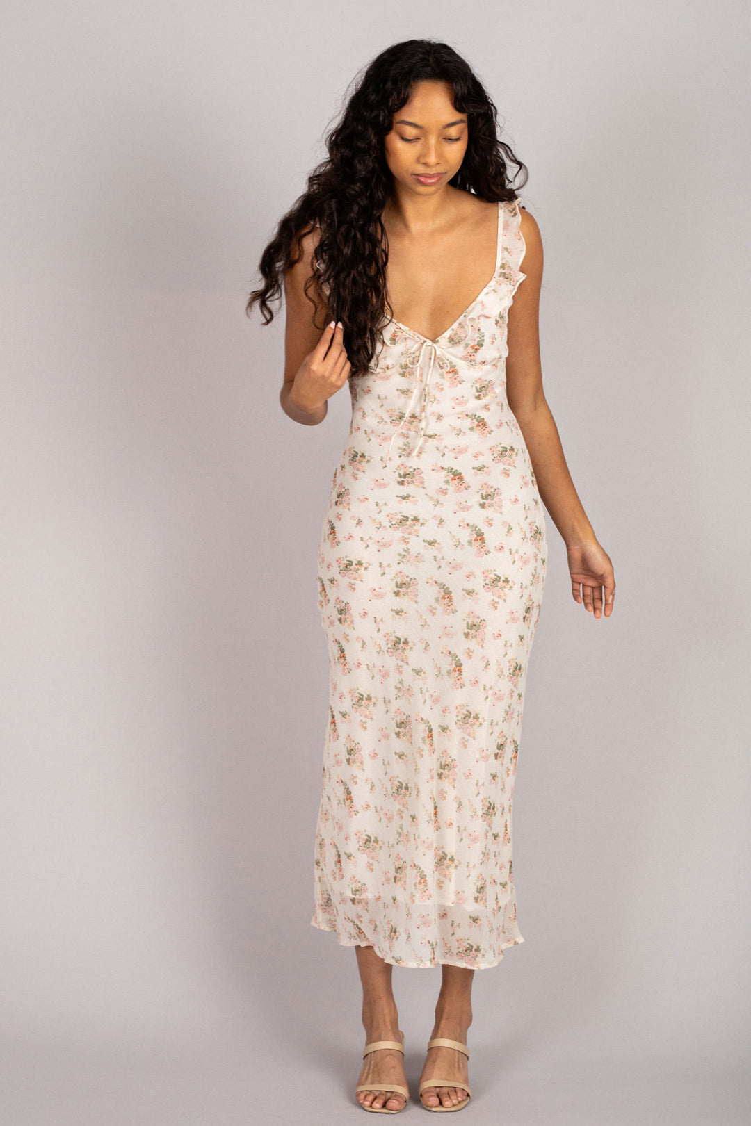 A floral chiffon dress with a plunging v-neck, fluttering sleeves, and a flowing, ankle-length skirt, modeled by a woman with long, dark curly hair.