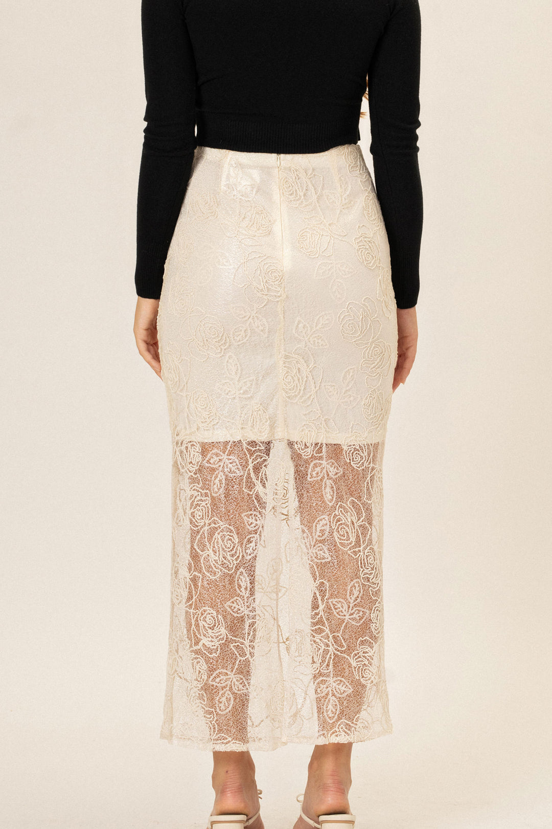 A white lace skirt with an elegant floral pattern, featuring a high waist and a midi length.