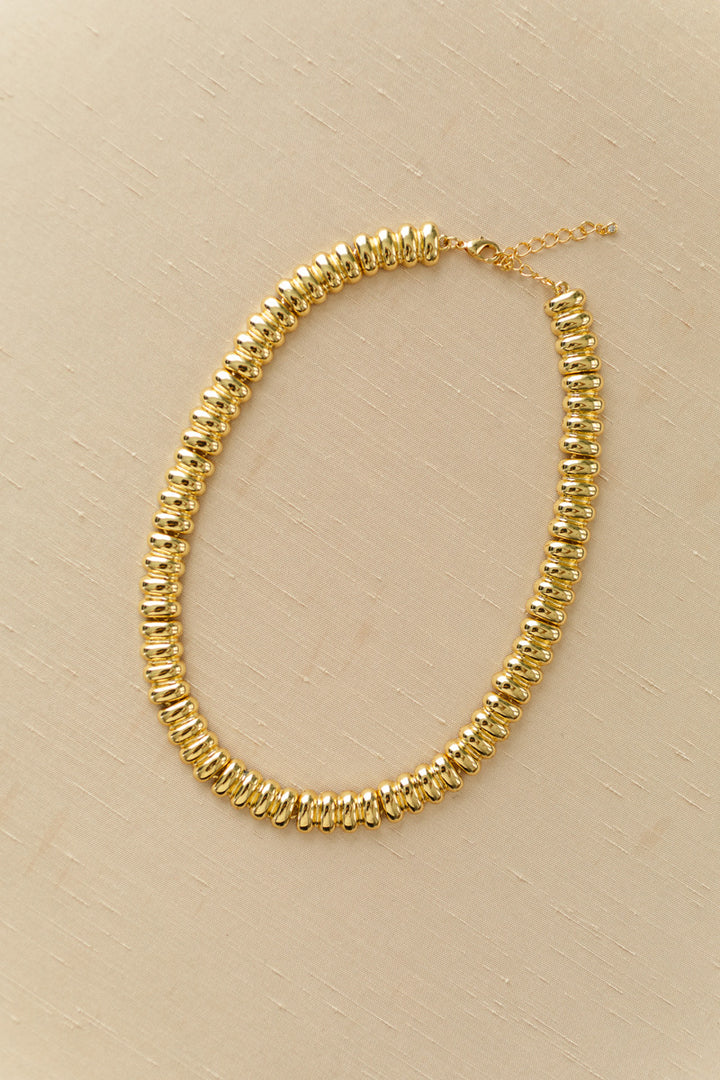 A stylish, gold-toned necklace featuring a series of interconnected discs that create a cohesive, eye-catching design.