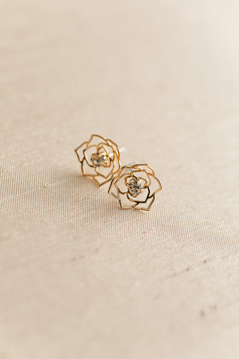 Gold-toned rose-shaped stud earrings with rhinestone centers, showcasing a delicate, floral design.