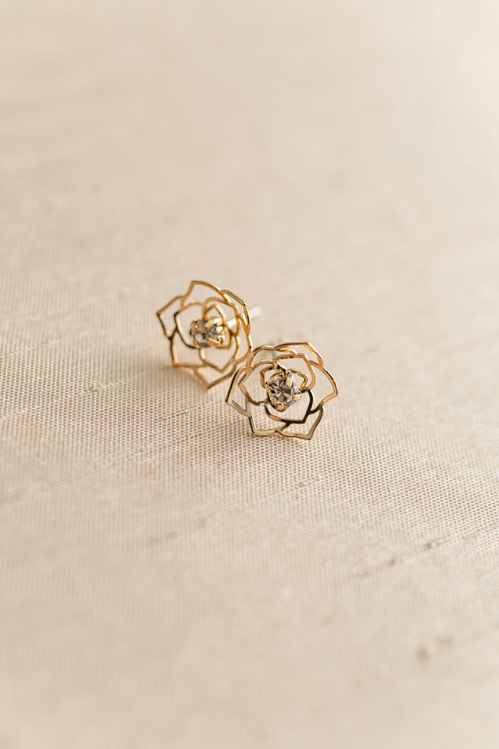 Gold-toned rose-shaped stud earrings with rhinestone centers, showcasing a delicate, floral design.
