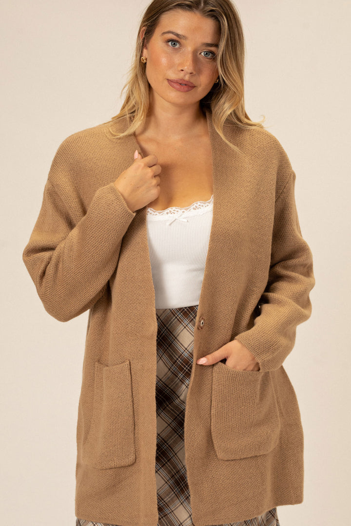 A tan knit cardigan with front pockets and a relaxed, casual fit.
