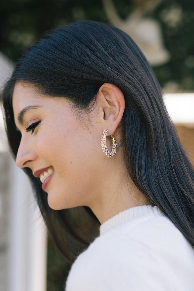Woman wearing gold hoop earrings with a blurred background