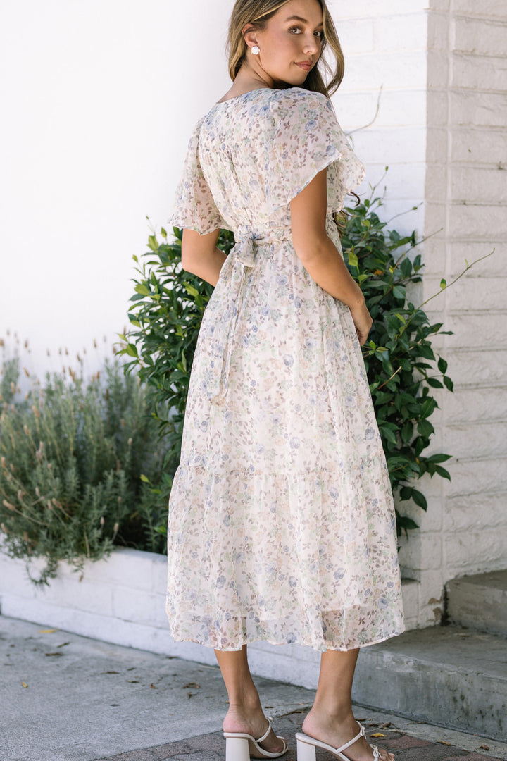 A floral print dress with flutter sleeves, cinched waist, and a midi-length skirt, creating a feminine and flowing silhouette.