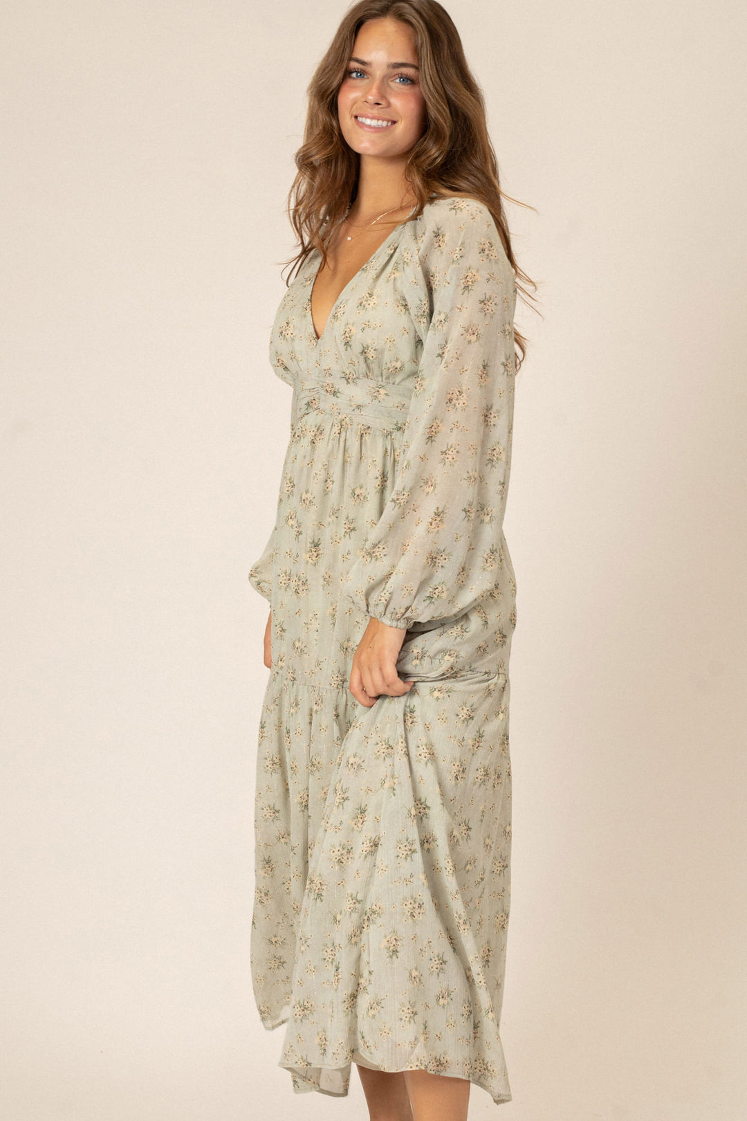 A long-sleeved midi dress in a soft beige floral print, with a v-neckline and billowing sleeves, showcasing a feminine, romantic style.