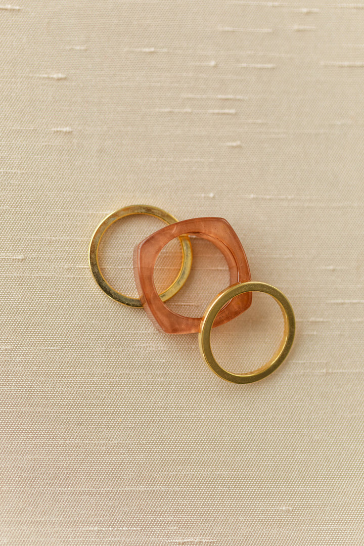 Three stacking rings in gold and peach tones, featuring a unique sculptural design.