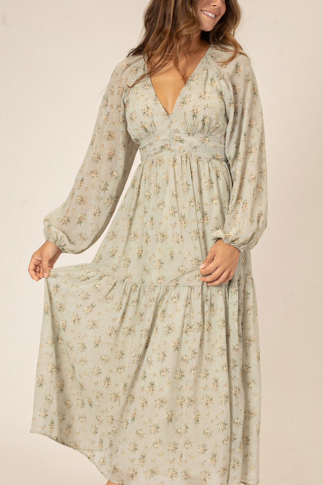 A long-sleeve maxi dress in a soft beige floral print, with a v-neck, puff sleeves, and a ruffle hem for a flowy, romantic look.