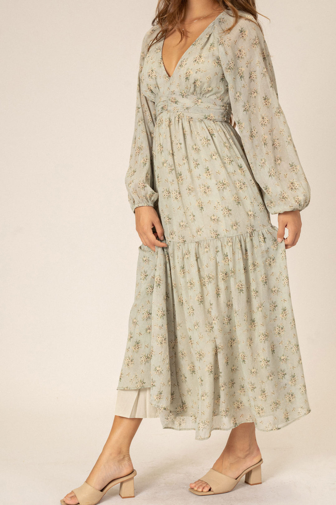 A long-sleeved, flowing midi dress in a soft, floral print with a v-neckline and tiered, ruffled skirt.