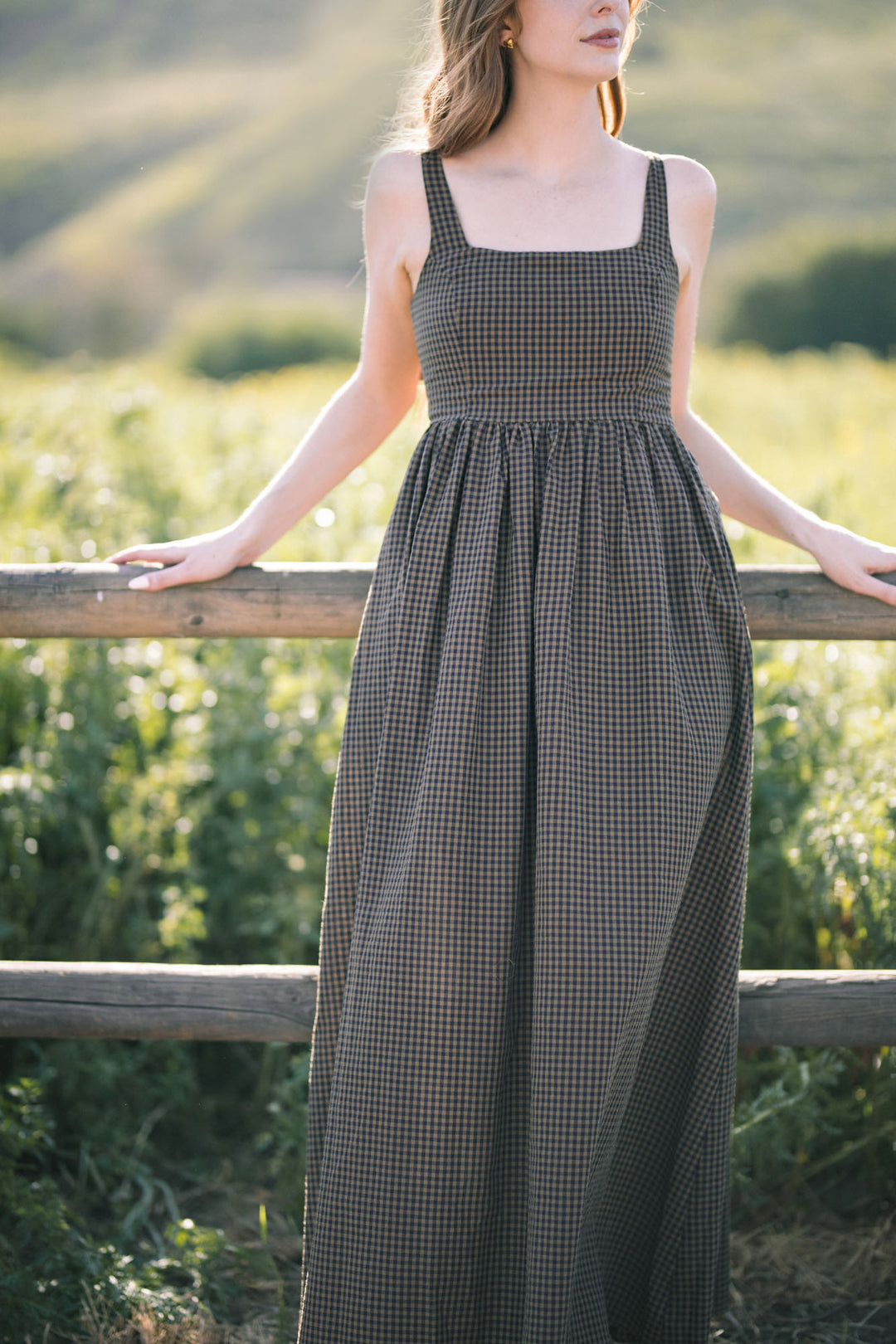 A sleeveless gingham maxi dress in a black and white checkered pattern, featuring a fitted bodice and a full, flowing skirt.