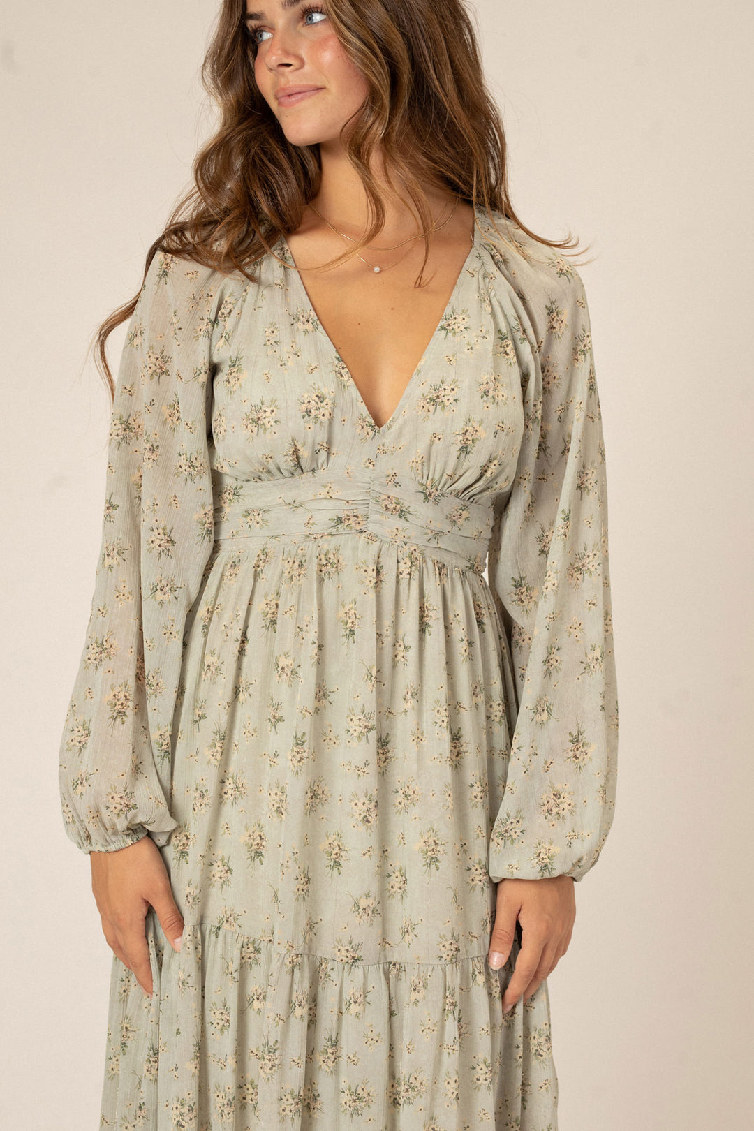 Flowing long-sleeved dress in a soft floral print, featuring a plunging v-neckline and voluminous sleeves. The dress has a smocked waist for a flattering fit.