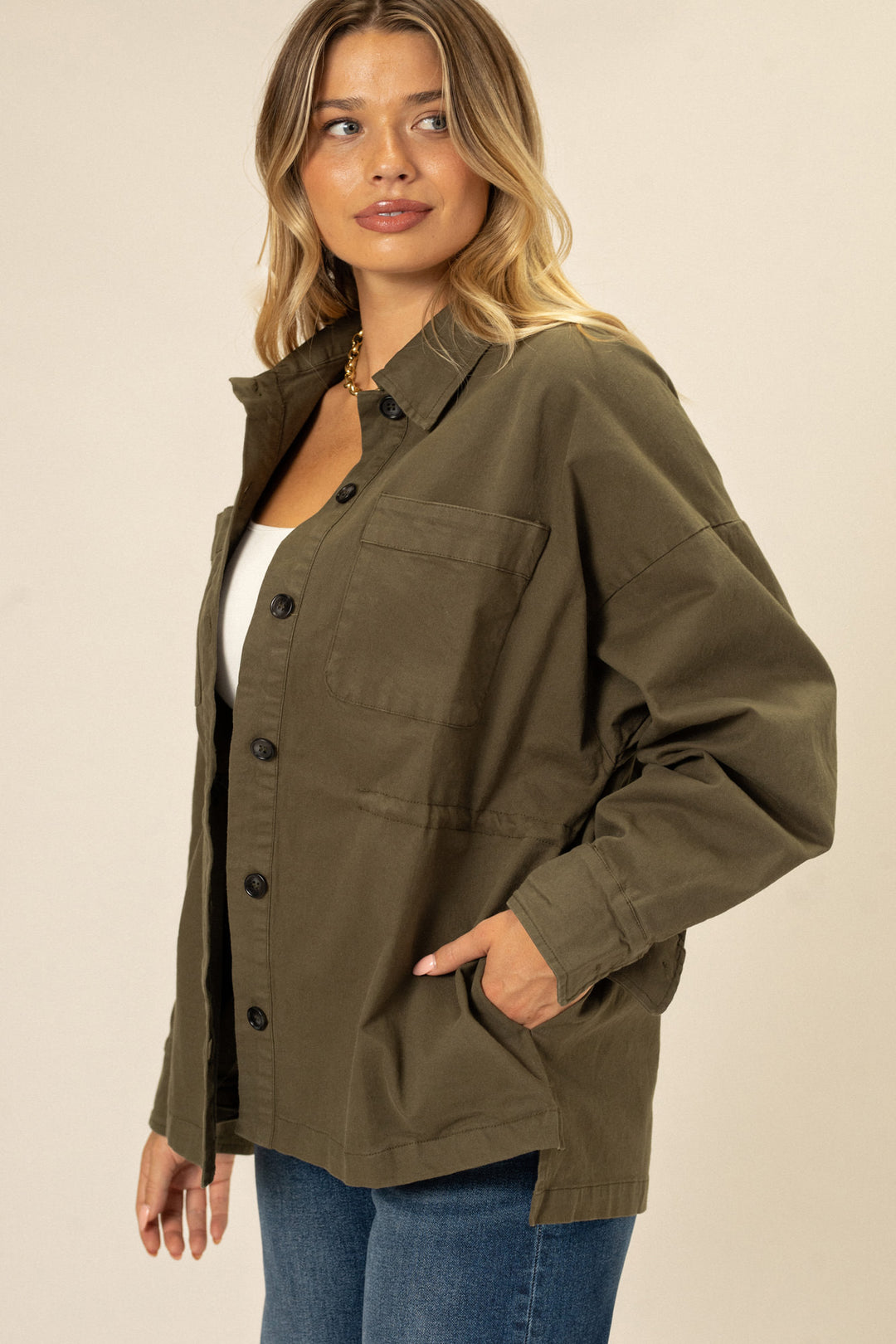 A khaki-colored button-up jacket with a cinched waist and oversized fit, featuring large front pockets and a relaxed silhouette.
