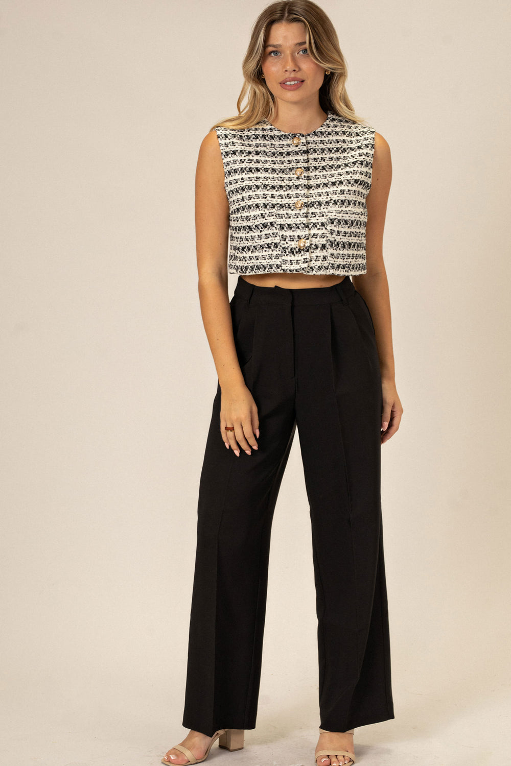 A woman wears black wide-leg pants and a patterned crop top, showcasing the style and fit of the Marnie Wide Leg Pants.