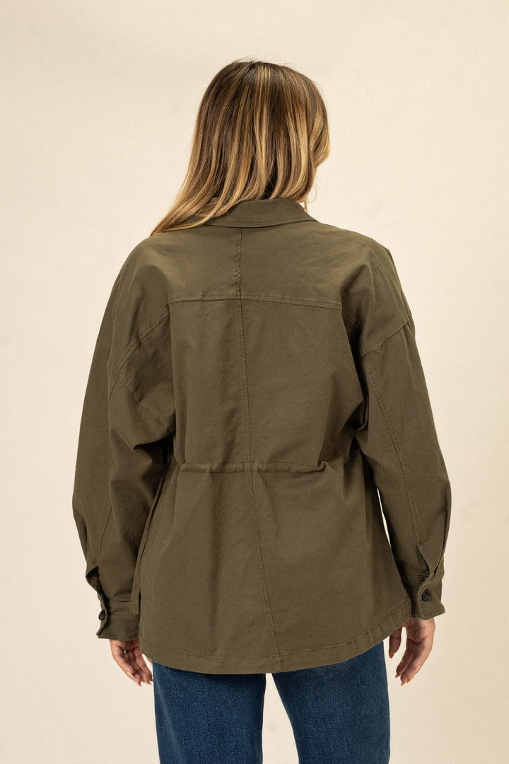 Olive green cinch waist jacket with button closure and roomy silhouette, shown on model with blonde hair.