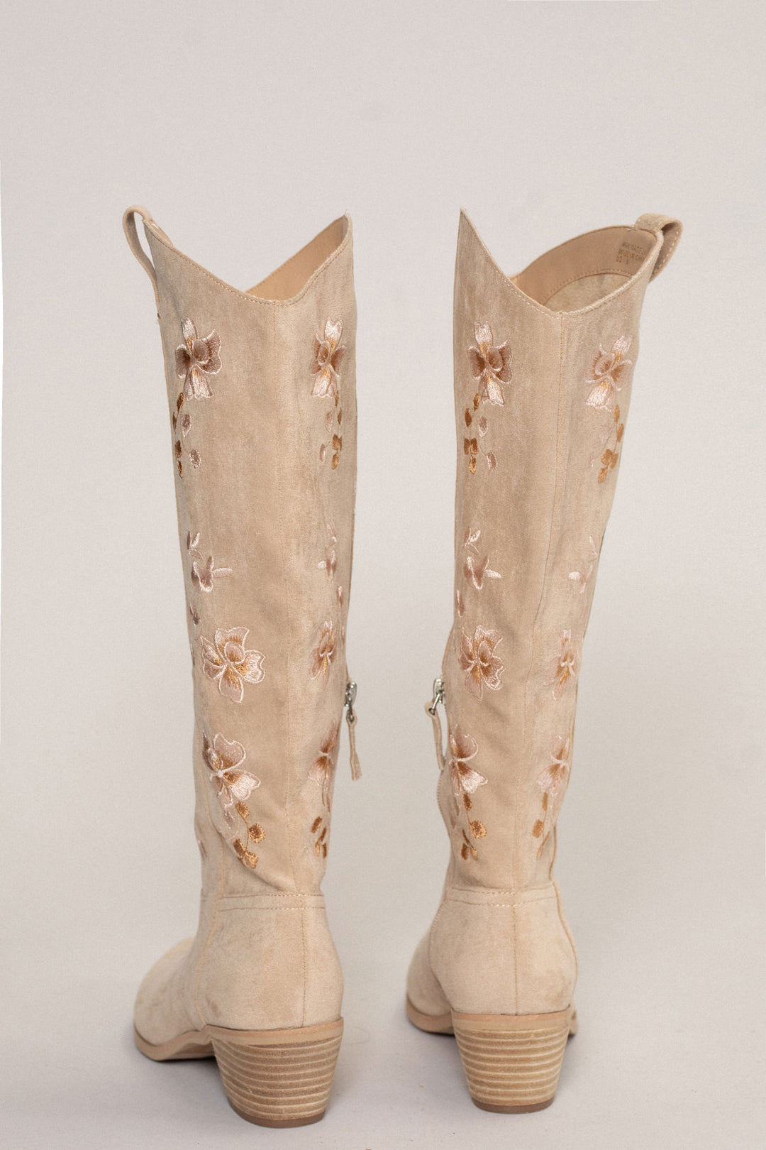 Tan suede western-style boots with floral embroidered design and chunky heels.