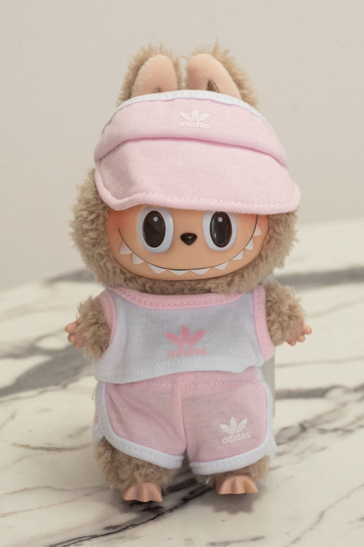 A plush, gray and pink stuffed animal wearing an Adidas visor, tank top, and shorts with the Adidas logo.