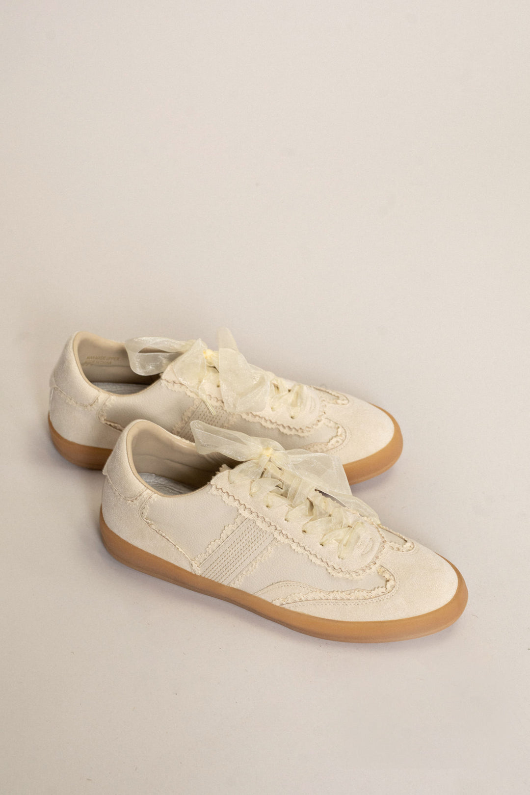 Cream-colored lace and tulle sneakers with gum rubber soles and contrast stitching.