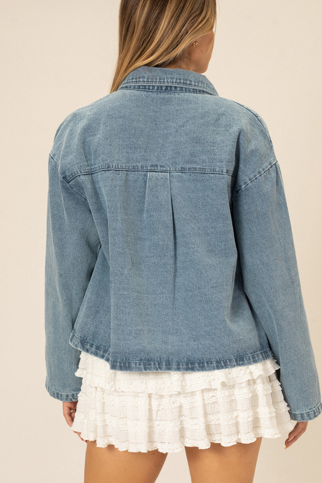 A light blue denim jacket with button closure, featuring a relaxed fit and long sleeves.