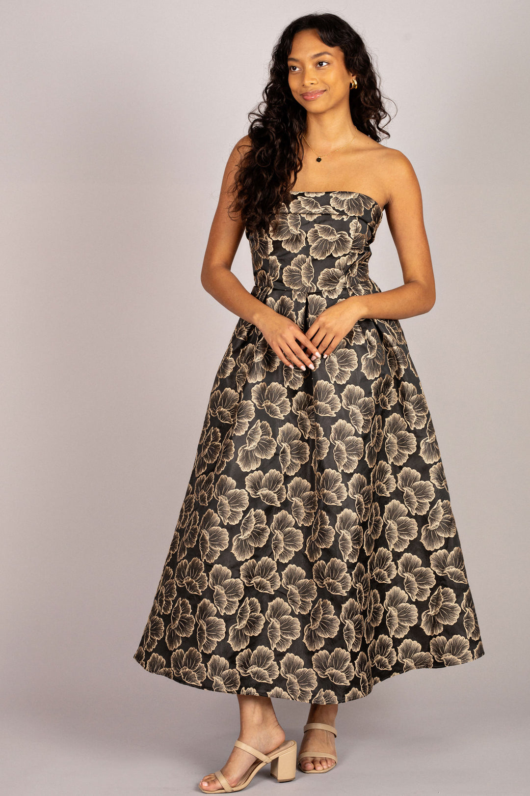 A strapless midi dress featuring a black and beige floral jacquard pattern, with a fitted bodice and a full, voluminous skirt.