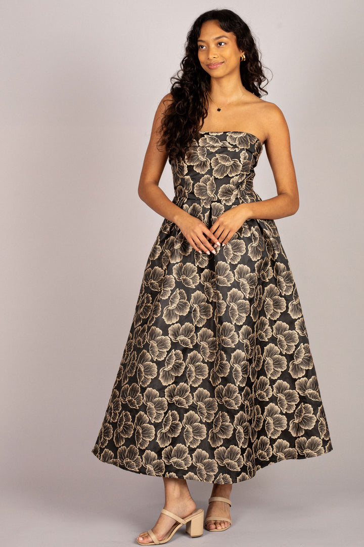 A strapless midi dress featuring a black and beige floral jacquard pattern, with a fitted bodice and a full, voluminous skirt.