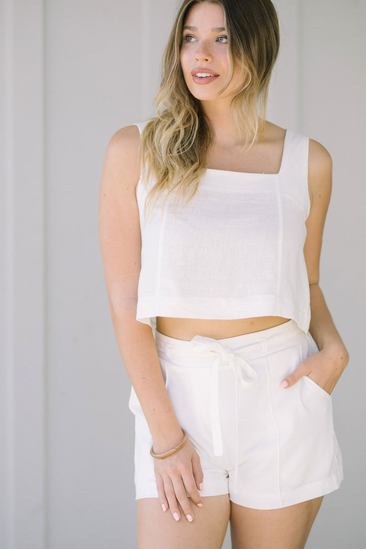 White square neck crop top with slim fit and billowy sleeves, modeled by a young woman with long, wavy blonde hair.