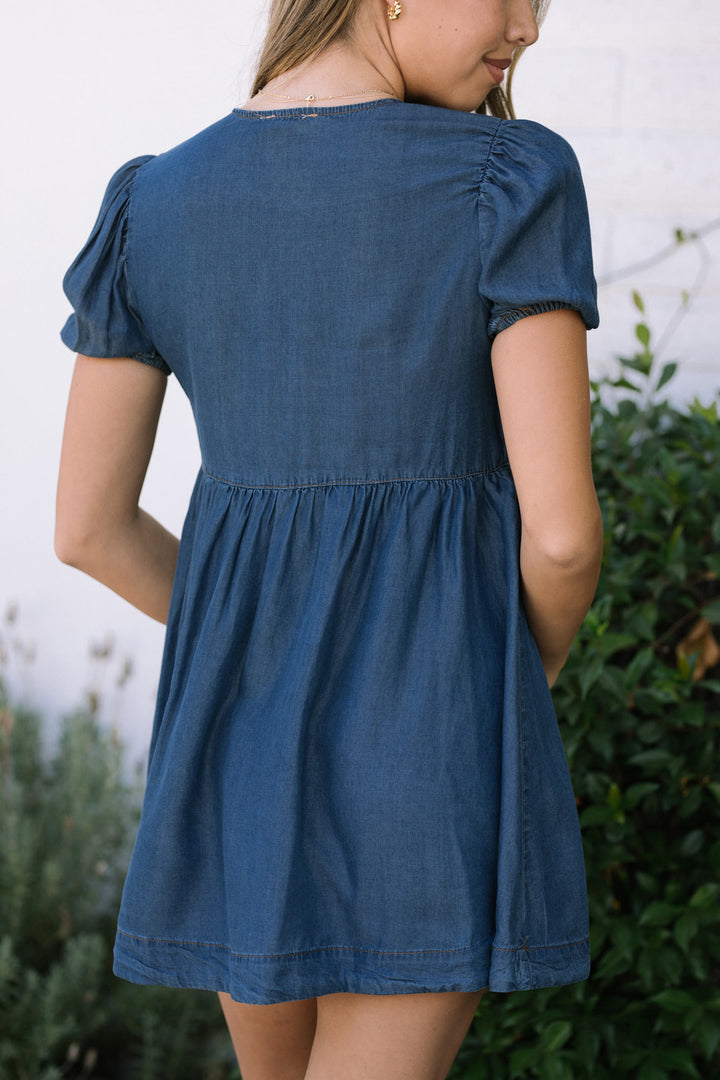 Chambray blue mini dress with puff sleeves, gathered waist, and flared skirt, perfect for casual summer outings.
