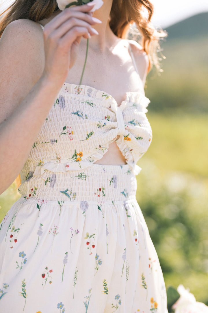 A floral-printed, white maxi dress with a smocked bodice and ruched, adjustable straps.