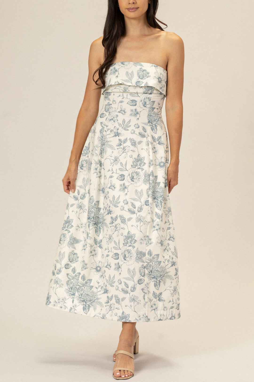 Strapless floor-length dress in a white and blue floral print, with a fitted bodice and flowy skirt.