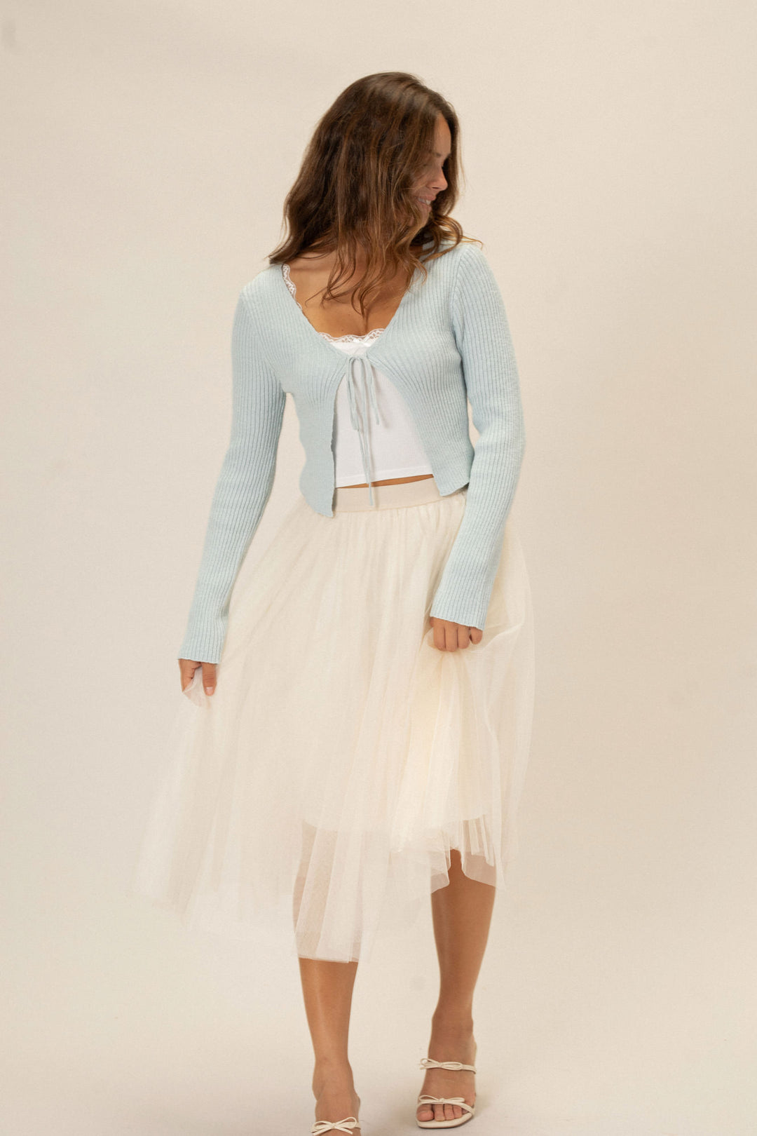 Light blue ribbed cropped top with a tie front detail, paired with a white tulle midi skirt and sandals.