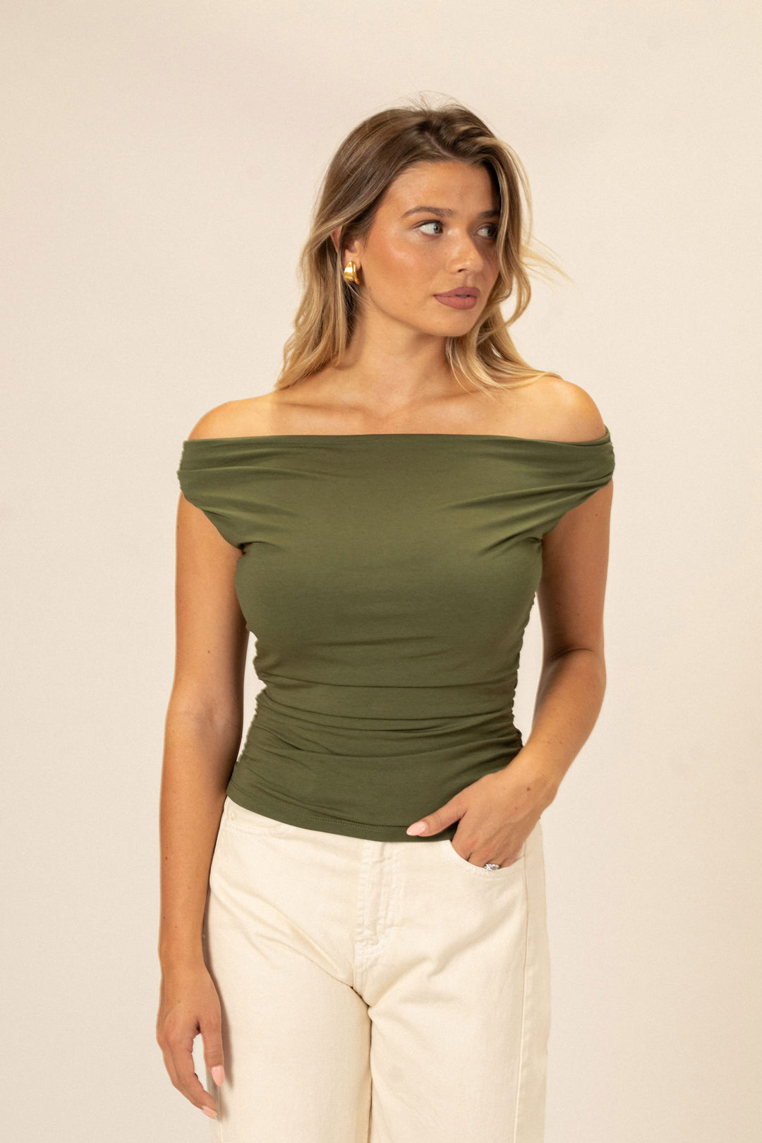 A figure-flattering olive green off-the-shoulder top with a fitted, stretchy fabric and a relaxed silhouette.