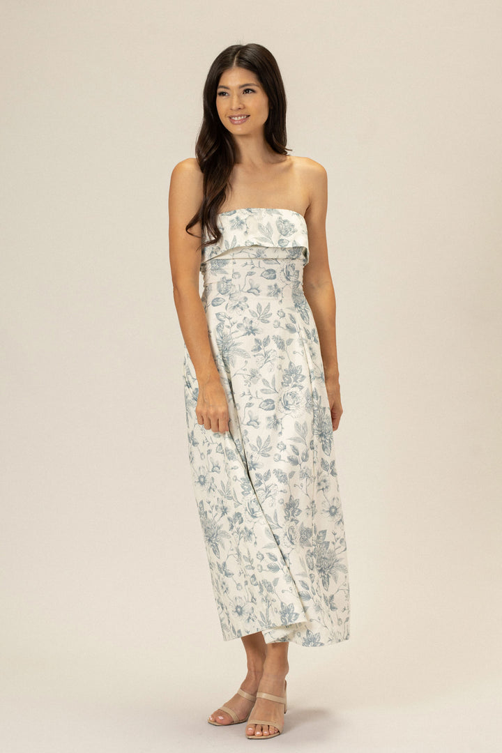 A strapless floral dress with a fitted bodice and flowing midi-length skirt in a soft, neutral color palette.