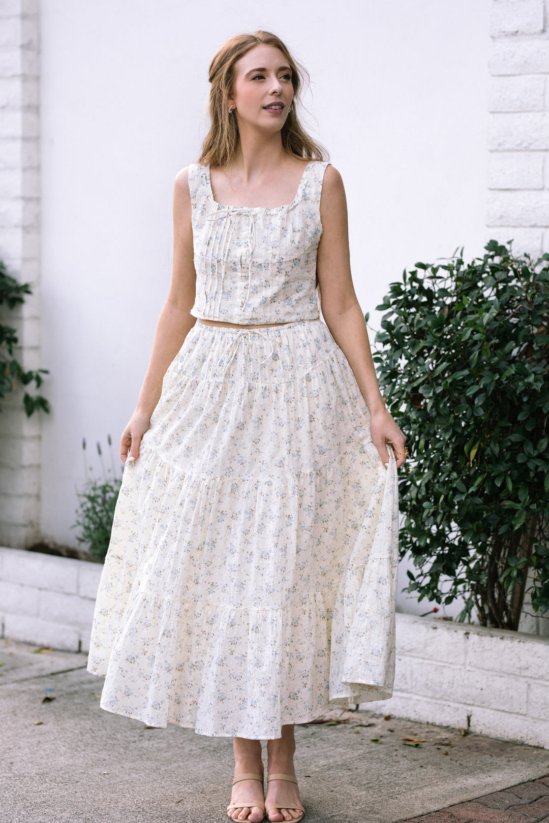 A floral sleeveless crop top with a pleated high-waist maxi skirt in a soft, ivory and blue floral print, featuring a fitted bodice and flowing, tiered skirt.