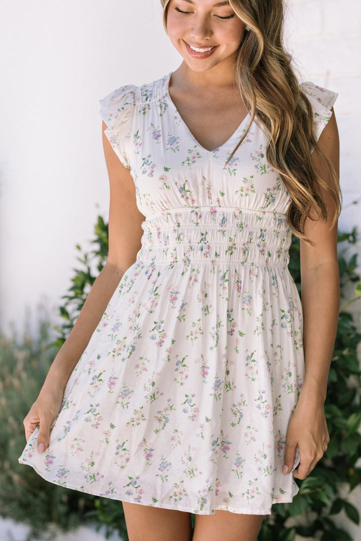 Floral print mini dress with ruffled cap sleeves, smocked waist, and flared skirt in a light, airy fabric.