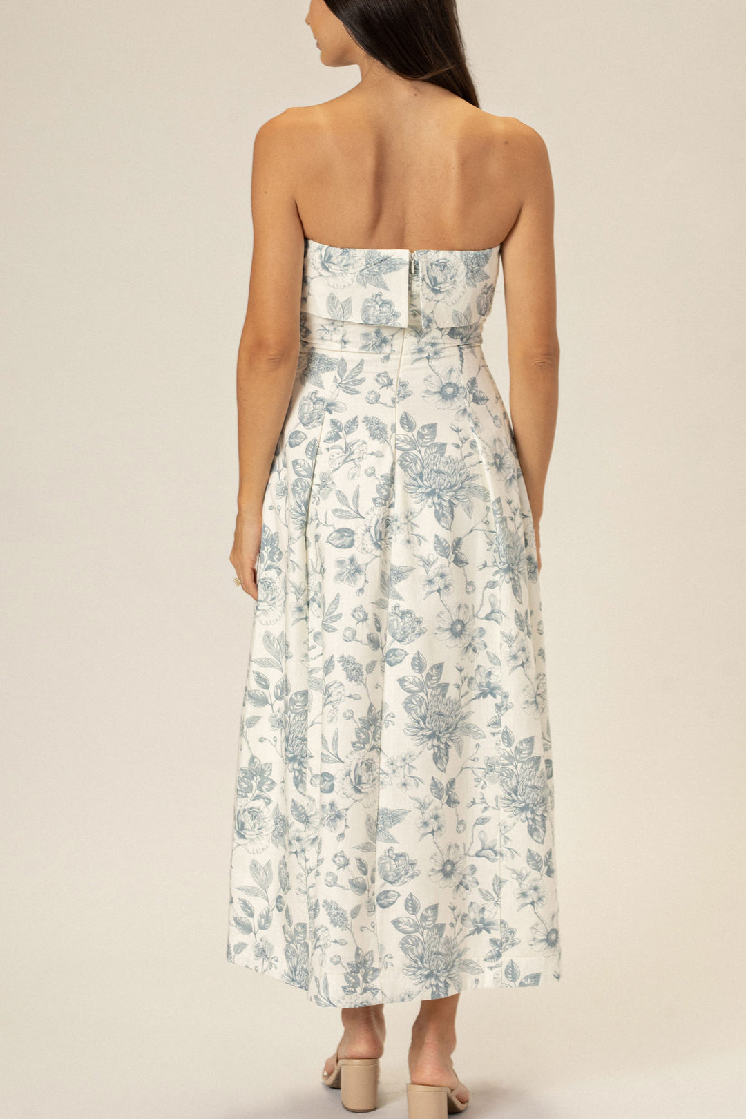 A strapless floral midi dress in a white and blue color palette, with a fitted bodice and a full, pleated skirt.