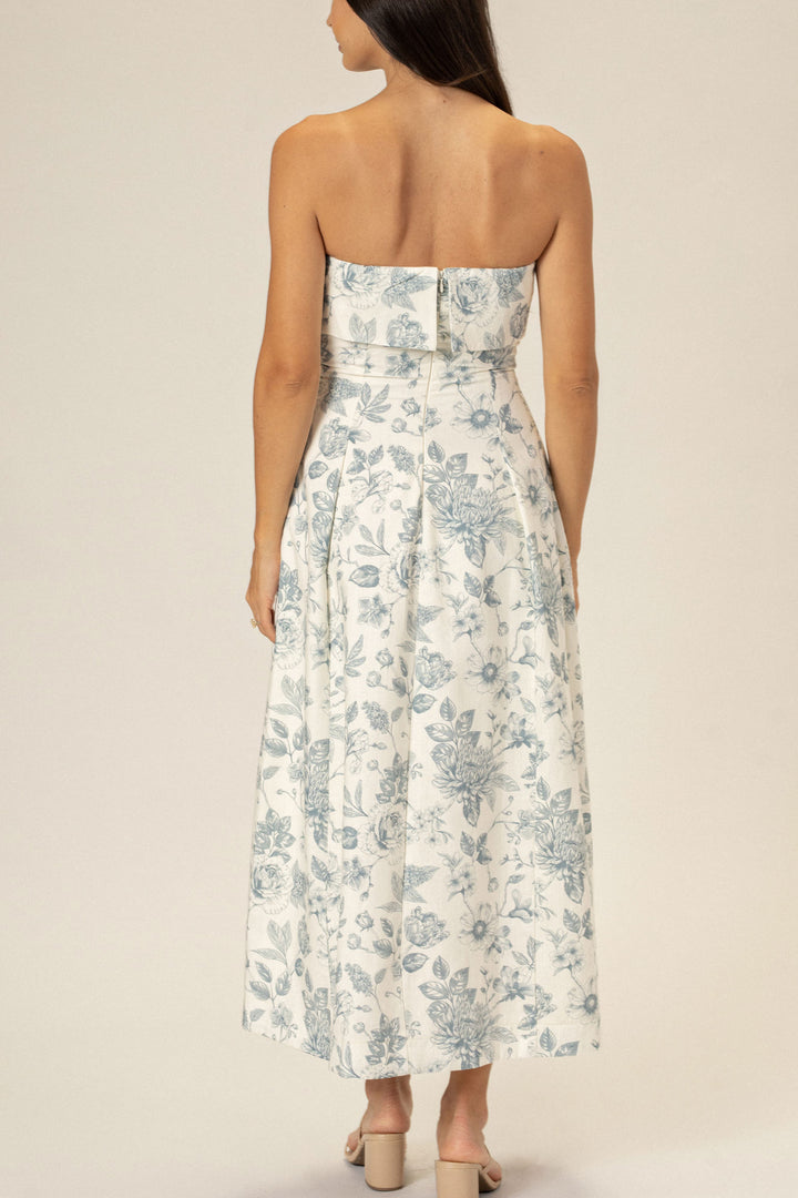 A strapless floral midi dress in a white and blue color palette, with a fitted bodice and a full, pleated skirt.