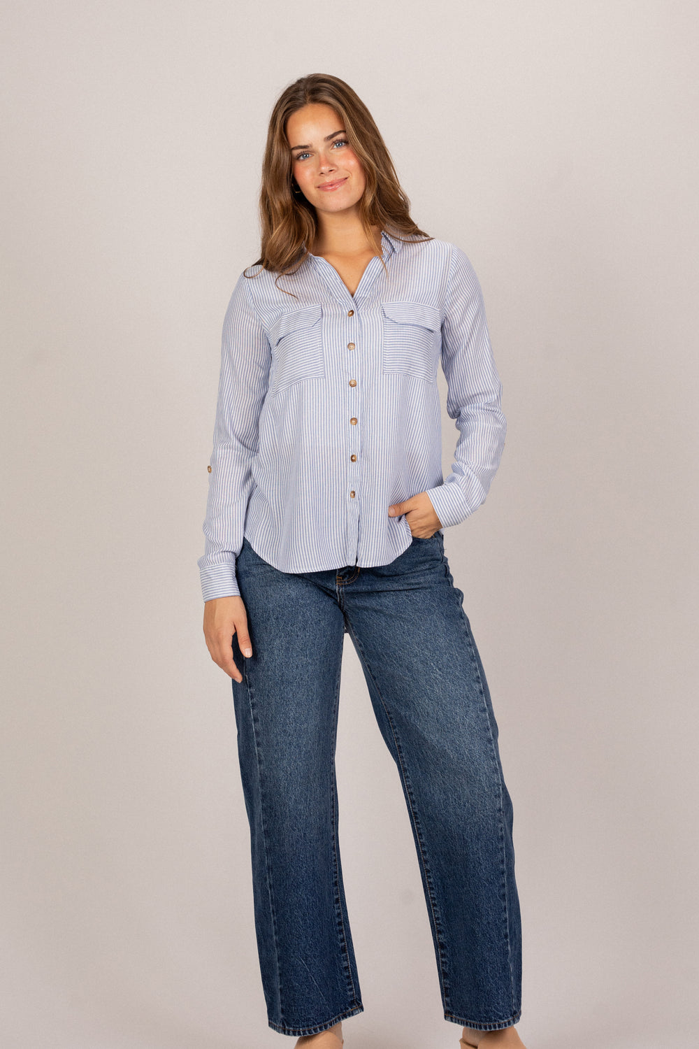 A blue and white striped button-up shirt with chest pockets, worn by a young woman with long brown hair.