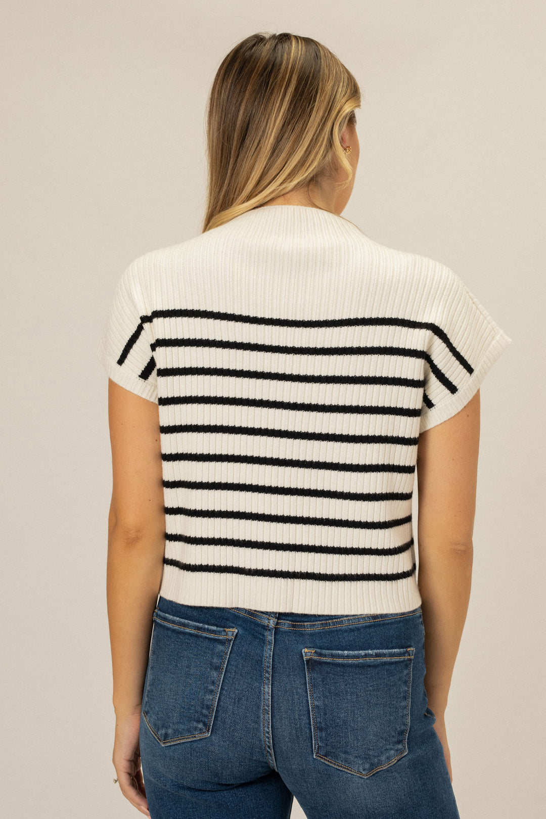 A white ribbed knit top with horizontal black stripes, featuring a mock neck design and a slim silhouette.