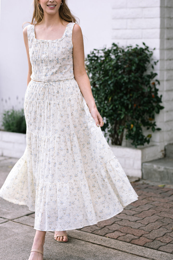 A white floral print midi skirt with a ruffled, tiered design and a matching sleeveless crop top, creating a coordinated set.