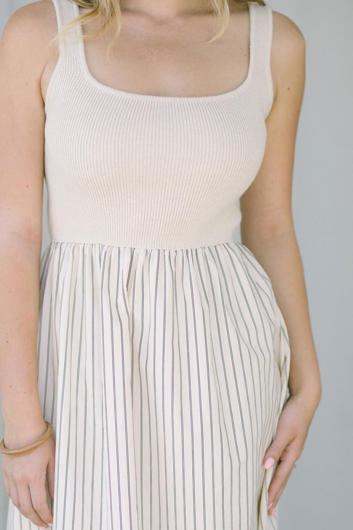 White and black striped dress with a ribbed knit bodice and pleated skirt.