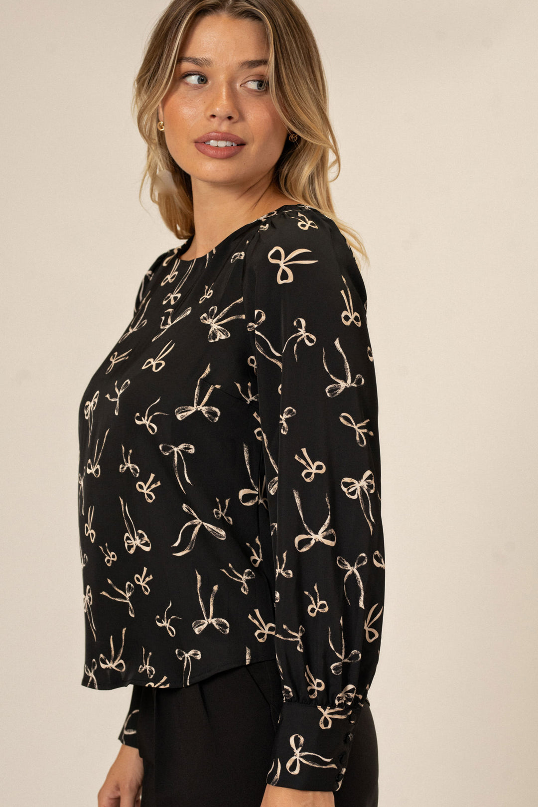 Black long sleeve blouse with allover bow pattern, featuring a relaxed, flowy silhouette.