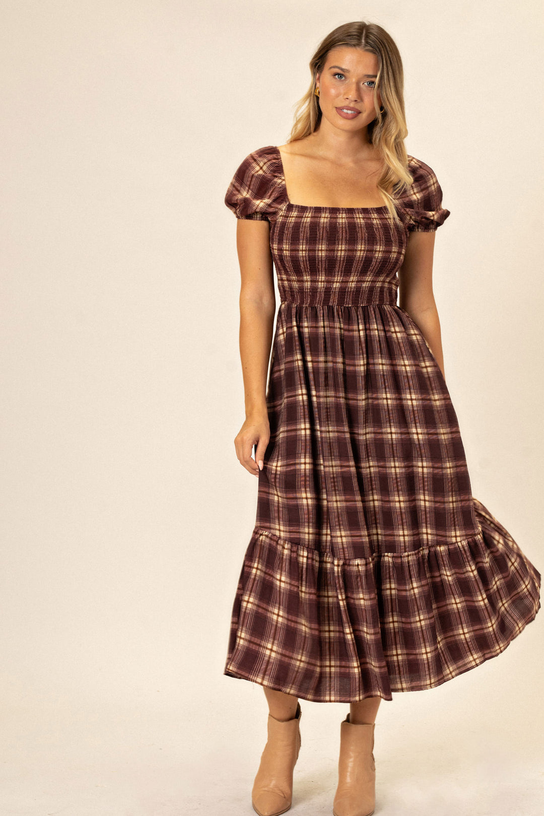 A burgundy and tan plaid dress with a fitted bodice, puffy sleeves, and a full, tiered skirt, creating a classic yet modern silhouette.
