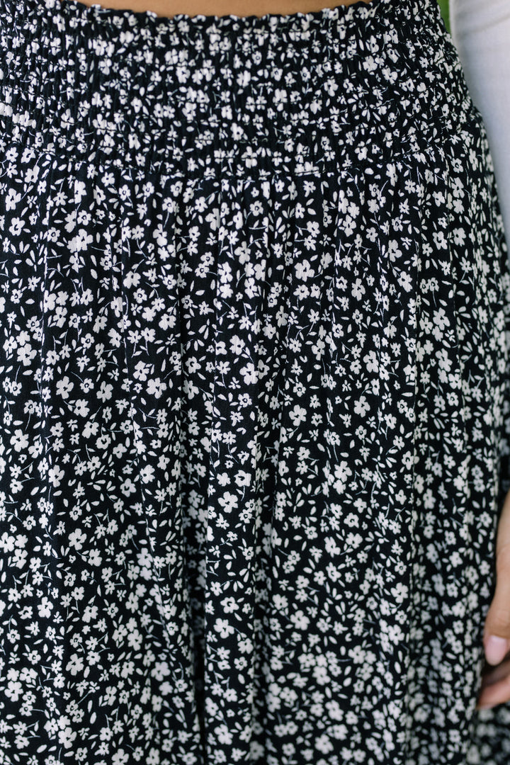 A black and white floral print skirt with a rounded hemline, featuring an elastic waistband for a comfortable, flattering fit.