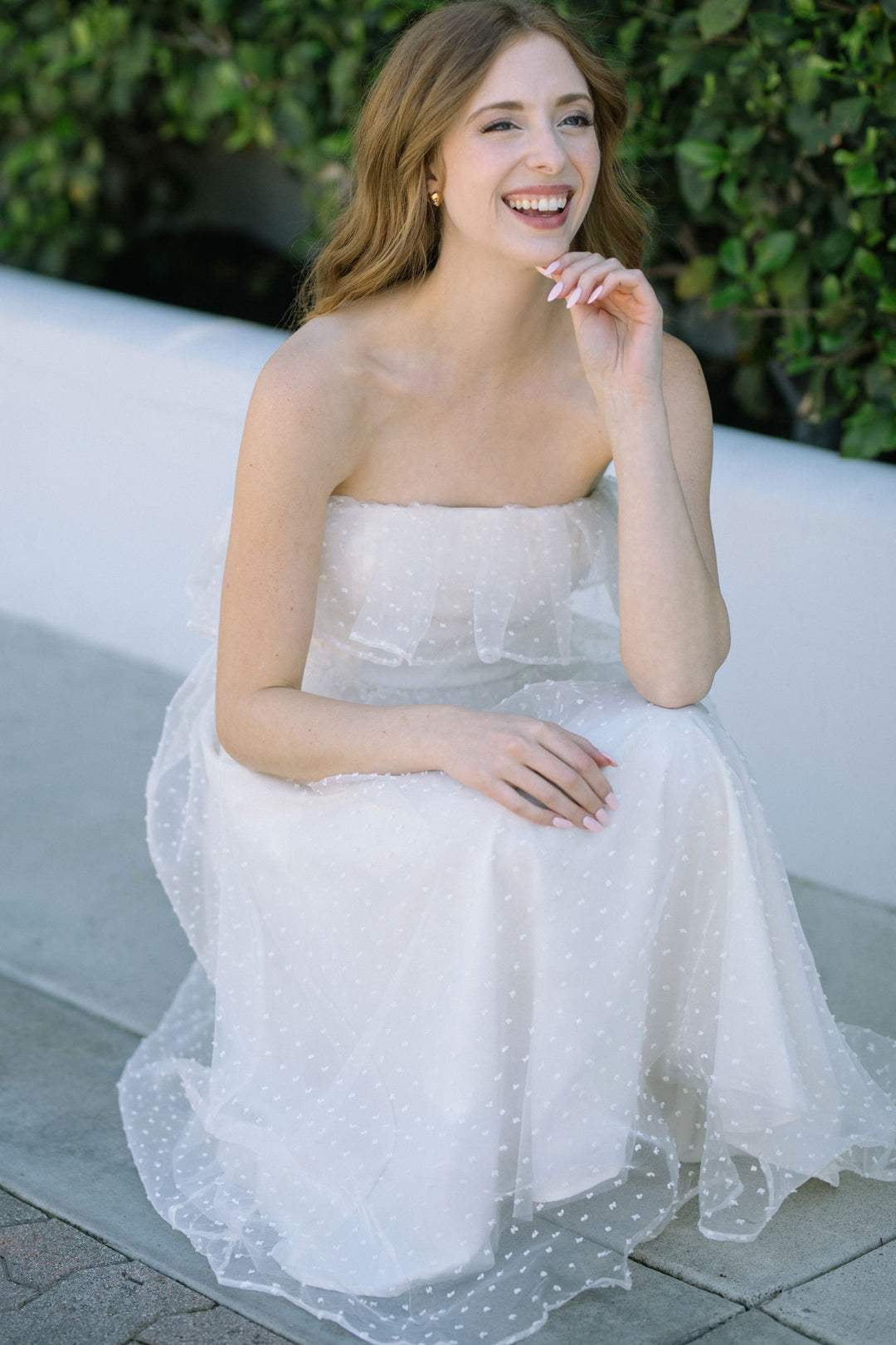 White strapless midi dress with polka dot tulle overlay, featuring a flared A-line silhouette and a smiling woman wearing the dress.