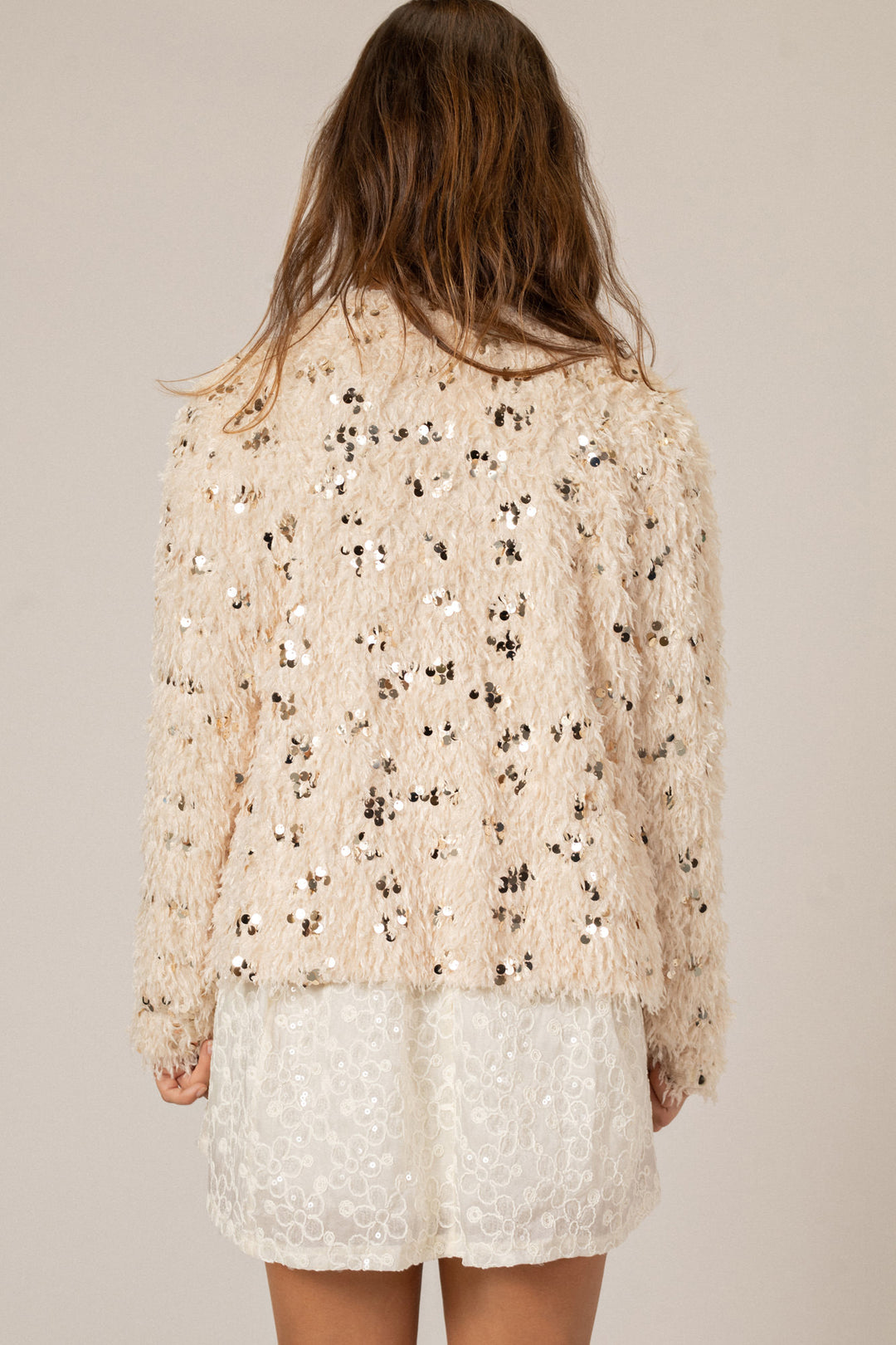 Soft, shaggy feather and sequin-embellished cream cardigan with long sleeves and open front.