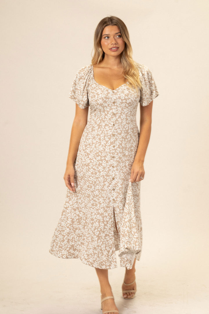A floral button-up dress in a neutral color palette, with flutter sleeves and a fitted bodice, featuring a high-low hem and a modest neckline.